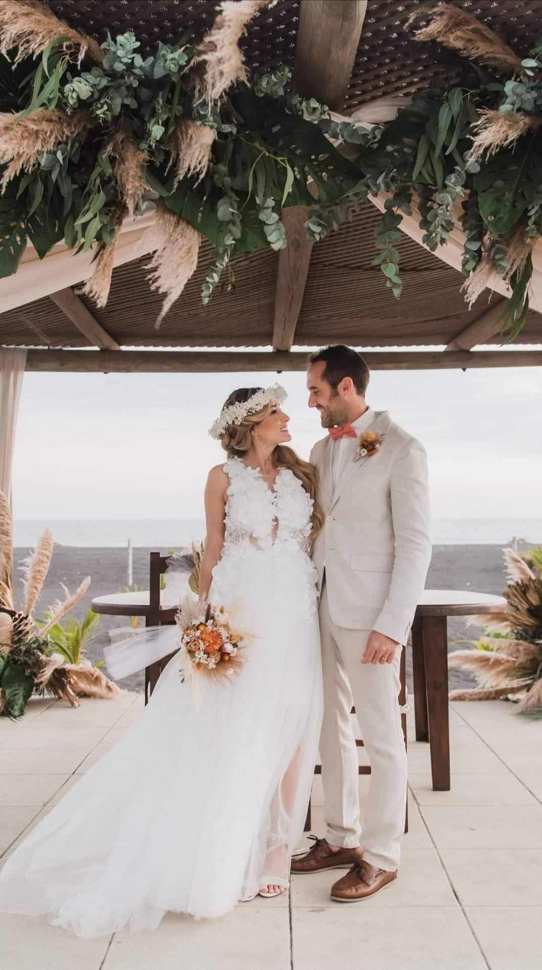 Novios en ceremonia frente al mar con decoración boho